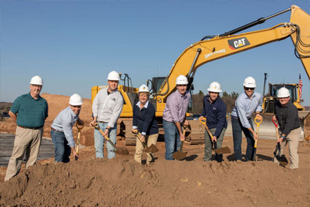 A group of people wearing hardhats and standing in a dirt field